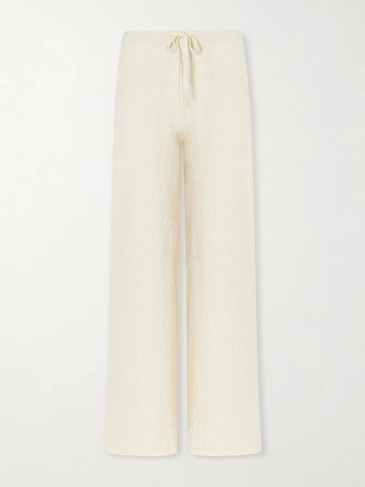 Image of a model wearing Pants. Product name - Calla Cotton-bouclé Flared Pants in Ecru colour by brand - Suzie Kondi