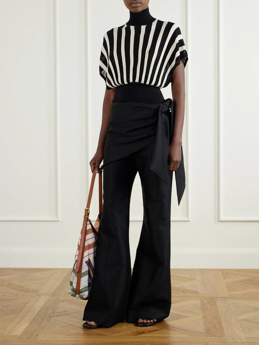 Image of a model wearing Pants. Product name - Tie-detailed Wool And Silk-blend Flared Pants in Black colour by brand - Zimmermann
