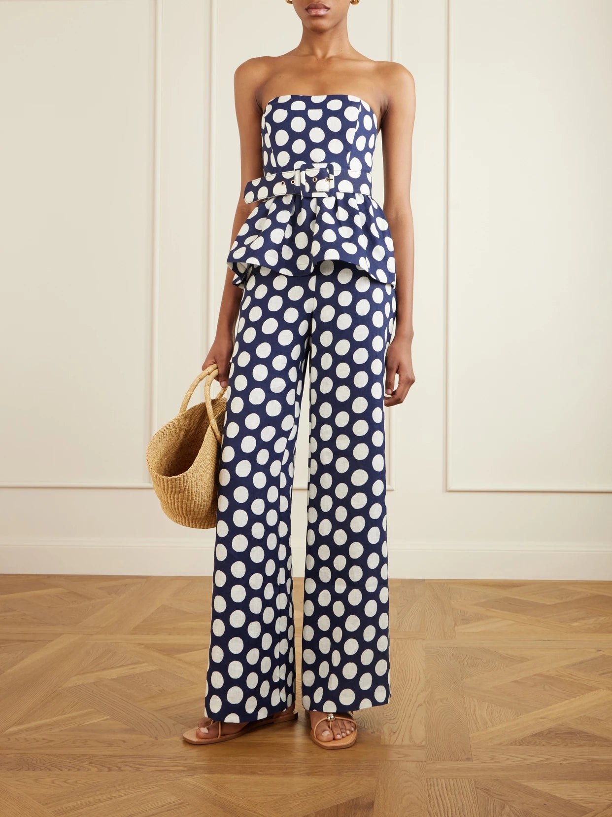 Image of a model wearing Tops. Product name - Tilda Strapless Belted Peplum Polka Dot Linen Top in Navy colour by brand - Cara Cara