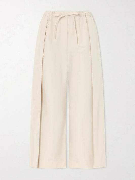 Image of a model wearing Pants. Product name - + Paula's Ibiza Pleated Cropped Cotton Wide-leg Pants in Beige colour by brand - LOEWE