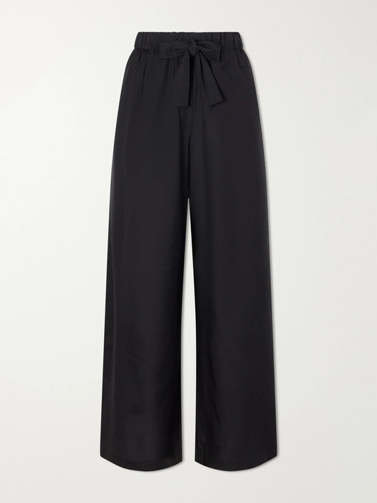 Image of a model wearing Pants. Product name - Silk Wide-leg Pants in Black colour by brand - TOTEME