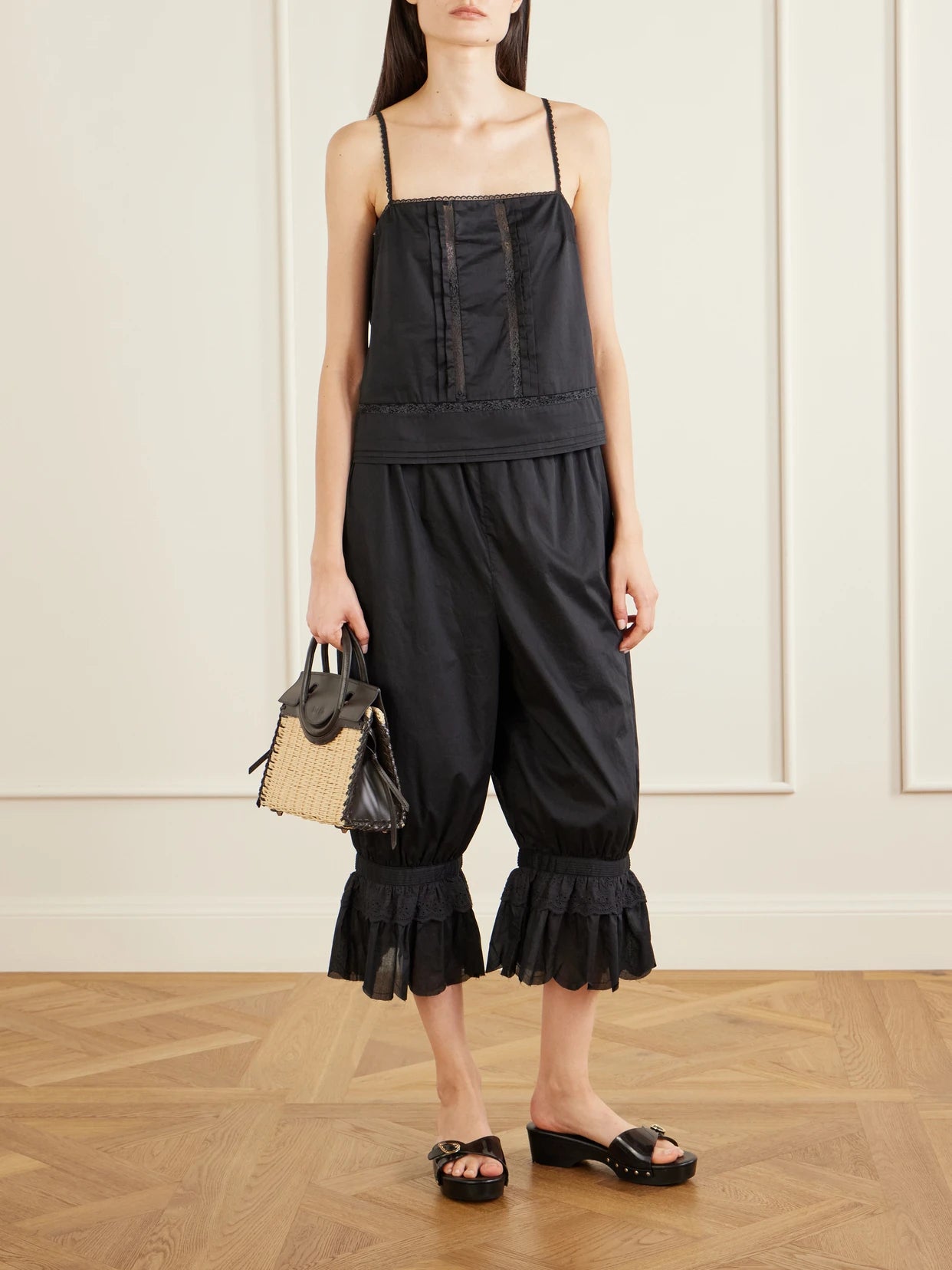 Image of a model wearing Pants. Product name - Renzo Cropped Scalloped Cotton-voile Balloon Pants in Black colour by brand - STAUD
