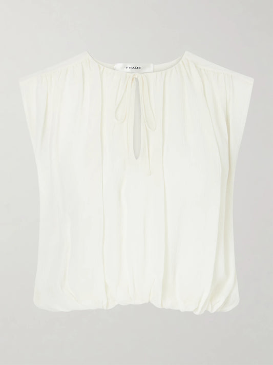 Image of a model wearing Tops. Product name - Wave Cropped Silk Top in Cream colour by brand - FRAME