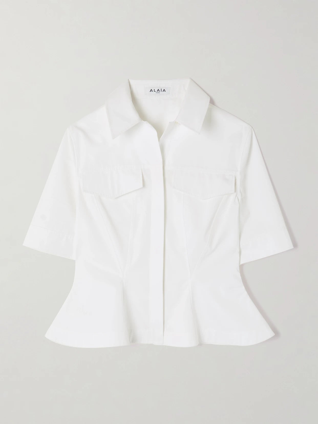 Image of a model wearing Tops. Product name - Paneled Cotton-poplin Peplum Shirt in White colour by brand - Alaïa