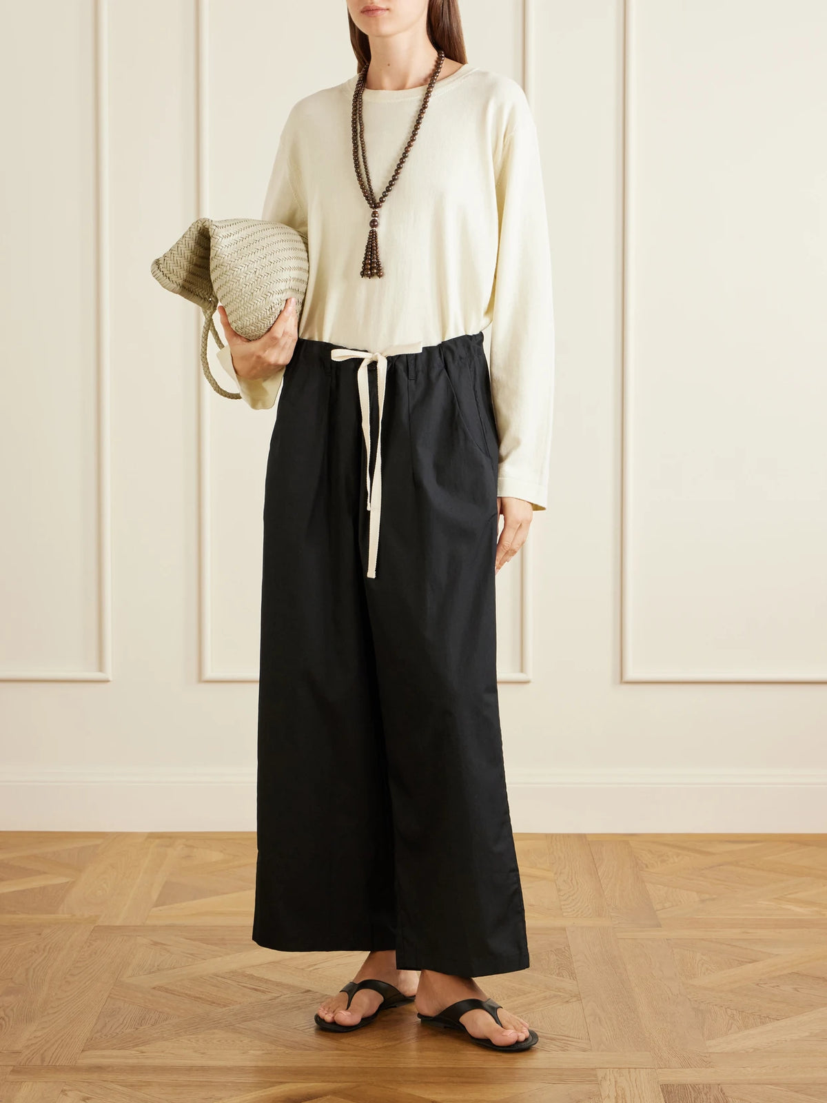 Image of a model wearing Pants. Product name - The Lotus Cotton-poplin Wide-leg Pants in Black colour by brand - Jamie Haller