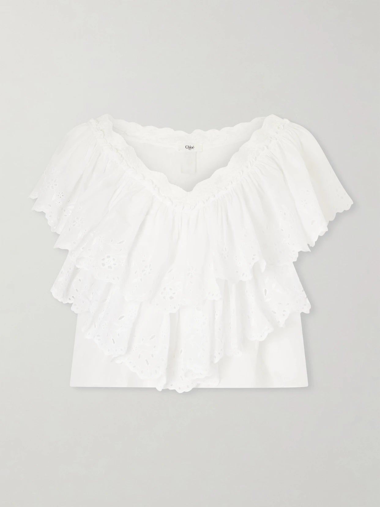 Image of a model wearing Tops. Product name - Cropped Ruffled Broderie Anglaise Cotton Top in White colour by brand - Chloé