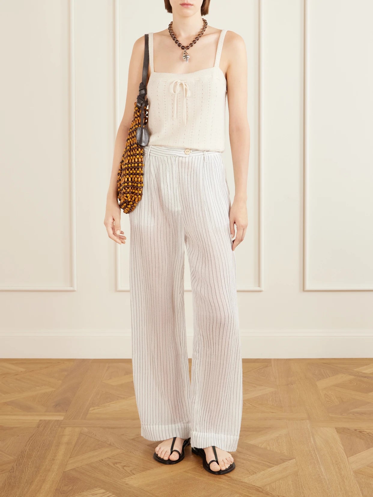 Image of a model wearing Pants. Product name - Diana Sea Salt Pleated Pinstriped Cotton-gauze Wide-leg Pants in White colour by brand - ALIX OF BOHEMIA