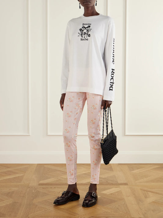 Image of a model wearing Pants. Product name - Ruffled Floral-print Pointelle-knit Cotton-jersey Leggings in Pastel pink colour by brand - Simone Rocha