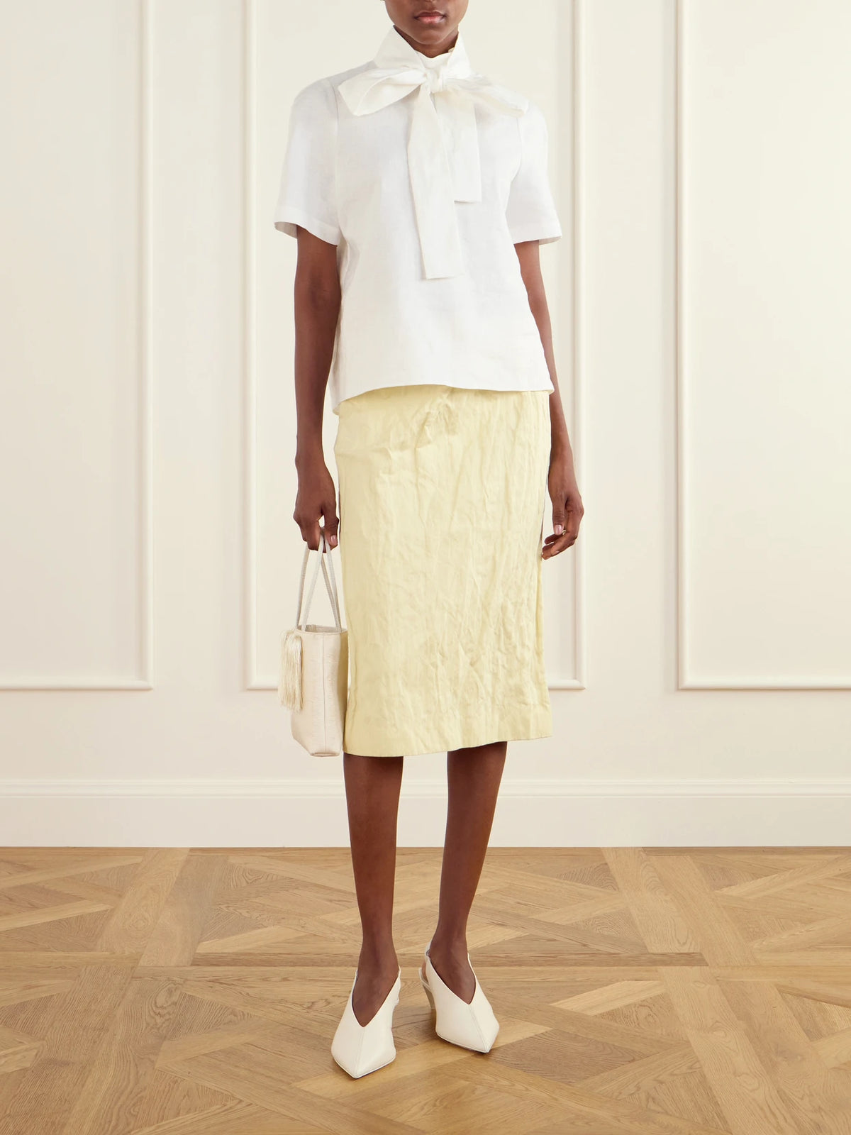 Image of a model wearing Skirts. Product name - Bow-detail Cotton-blend Midi Skirt in Pastel yellow colour by brand - SHUSHU/TONG