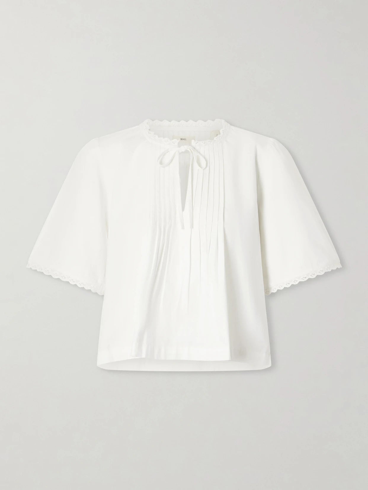 Image of a model wearing Tops. Product name - Freesia Pleated Lace-trimmed Organic Cotton Shirt in White colour by brand - SKALL