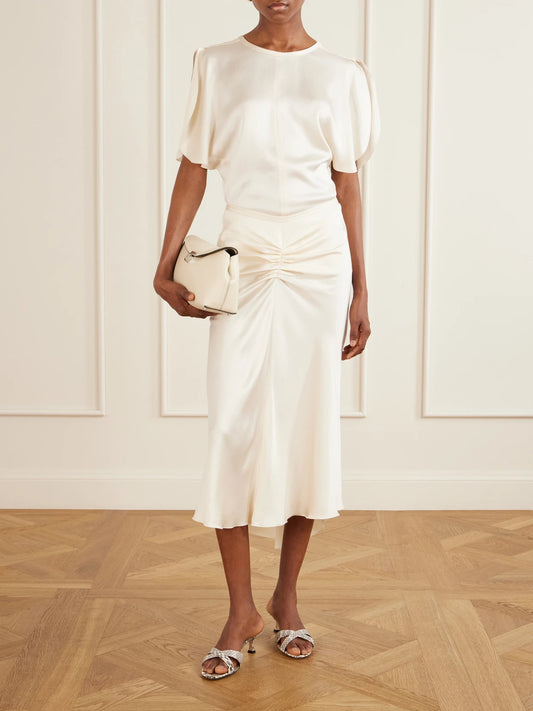 Image of a model wearing Skirts. Product name - Bela Ruched Satin Midi Skirt in Off-white colour by brand - Victoria Beckham