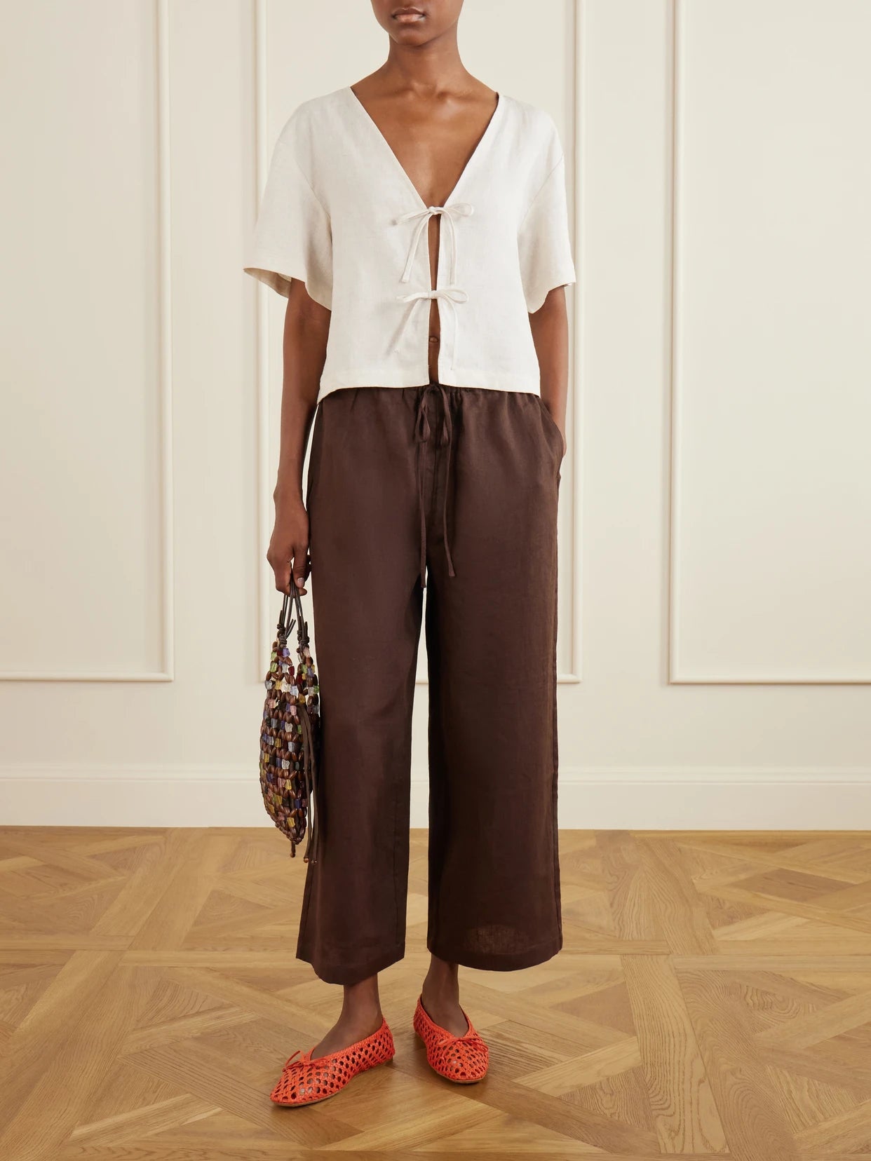 Image of a model wearing Pants. Product name - Mateo Linen Mid-rise Wide-leg Pants in Brown colour by brand - STAUD