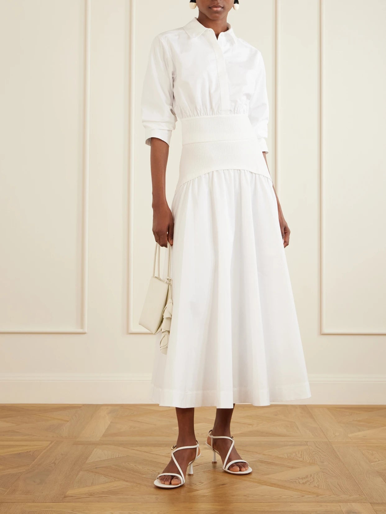 Image of a model wearing Skirts. Product name - Ovie Pleated Ribbed Cotton-poplin Midi Skirt in White colour by brand - SIMKHAI