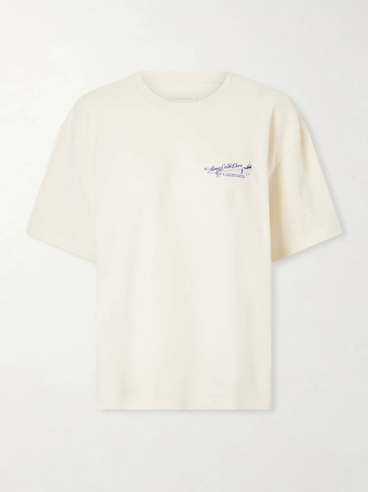 Image of a model wearing Tops. Product name - Logo-printed Cotton-jersey T-shirt in Off-white colour by brand - Aimé Leon Dore
