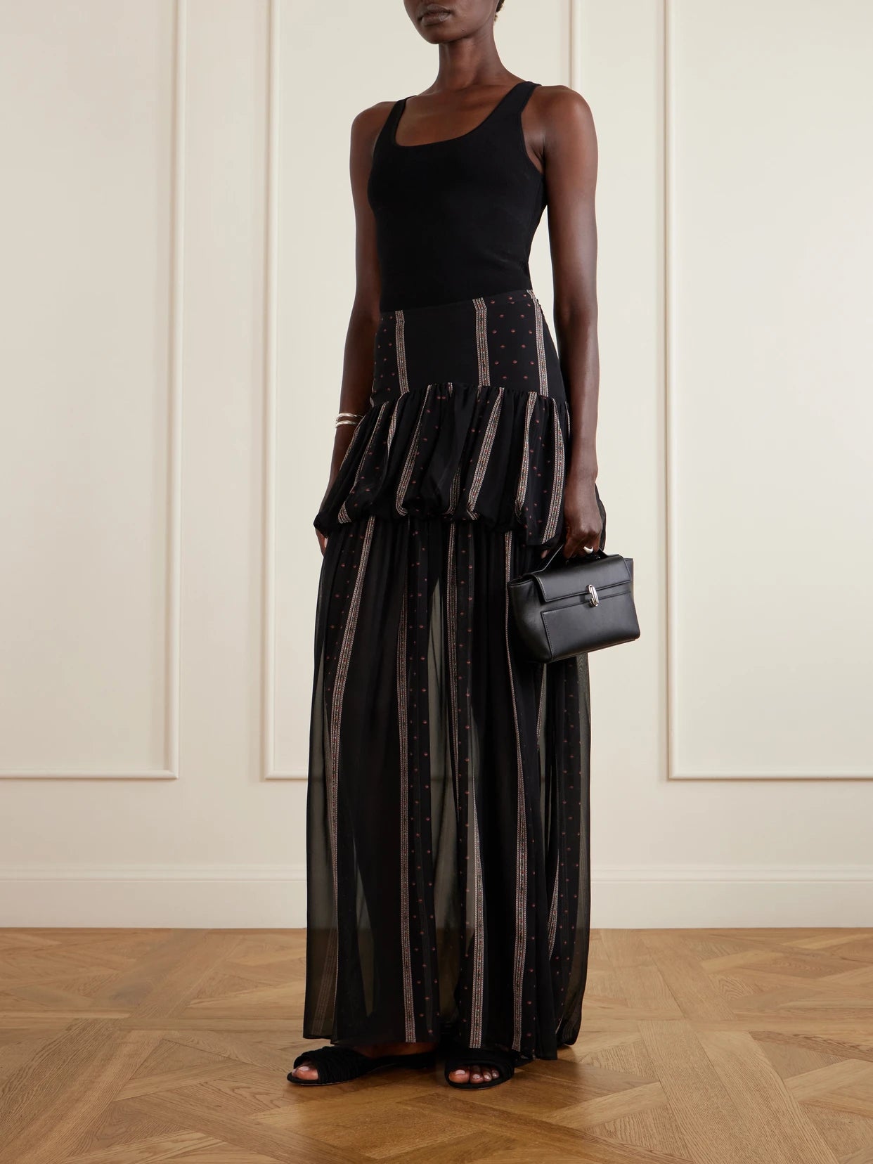 Image of a model wearing Skirts. Product name - Nina Striped Peplum Silk Maxi Skirt in Black colour by brand - LIBEROWE