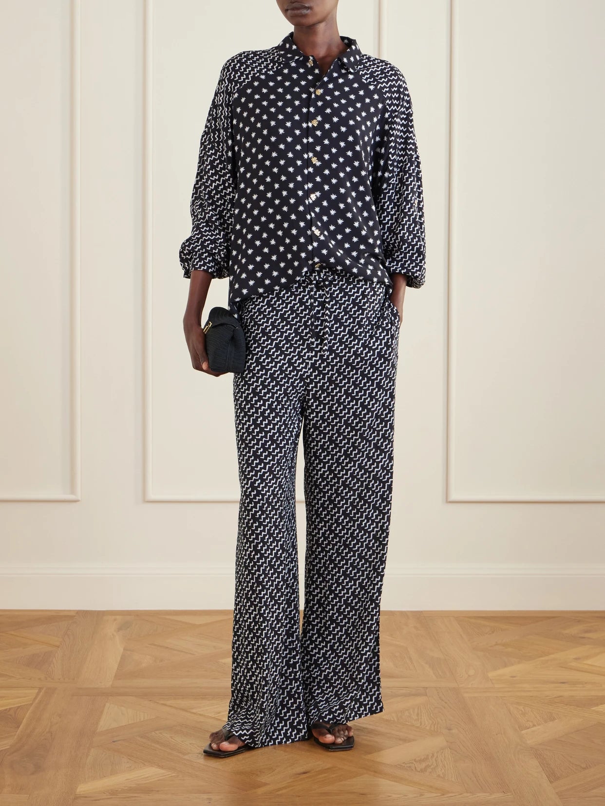 Image of a model wearing Pants. Product name - Estrellitas Y Olas Printed Woven Straight-leg Pants in Black colour by brand - Donde Esteban