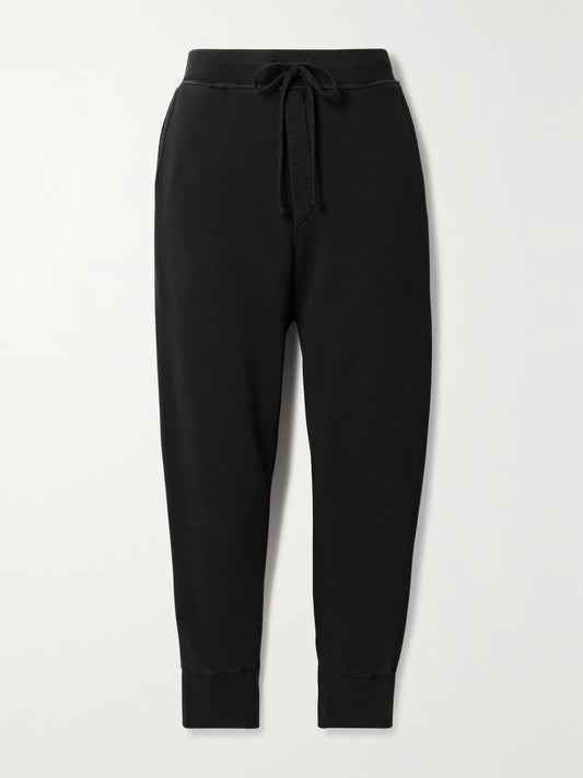 Image of a model wearing Pants. Product name - Nolan Cropped Cotton-jersey Track Pants in Black colour by brand - Nili Lotan