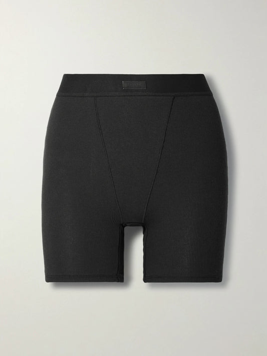 Image of a model wearing Shorts. Product name - Cotton Collection Ribbed Cotton-blend Jersey Boxer Shorts - Soot in Black colour by brand - SKIMS