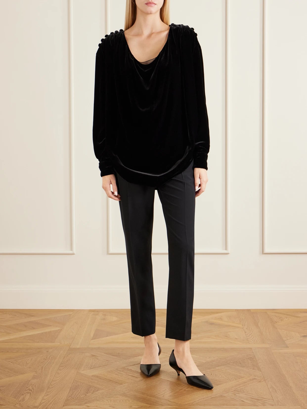 Image of a model wearing Tops. Product name - Ruched Button-embellished Velvet Blouse in Black colour by brand - The Row