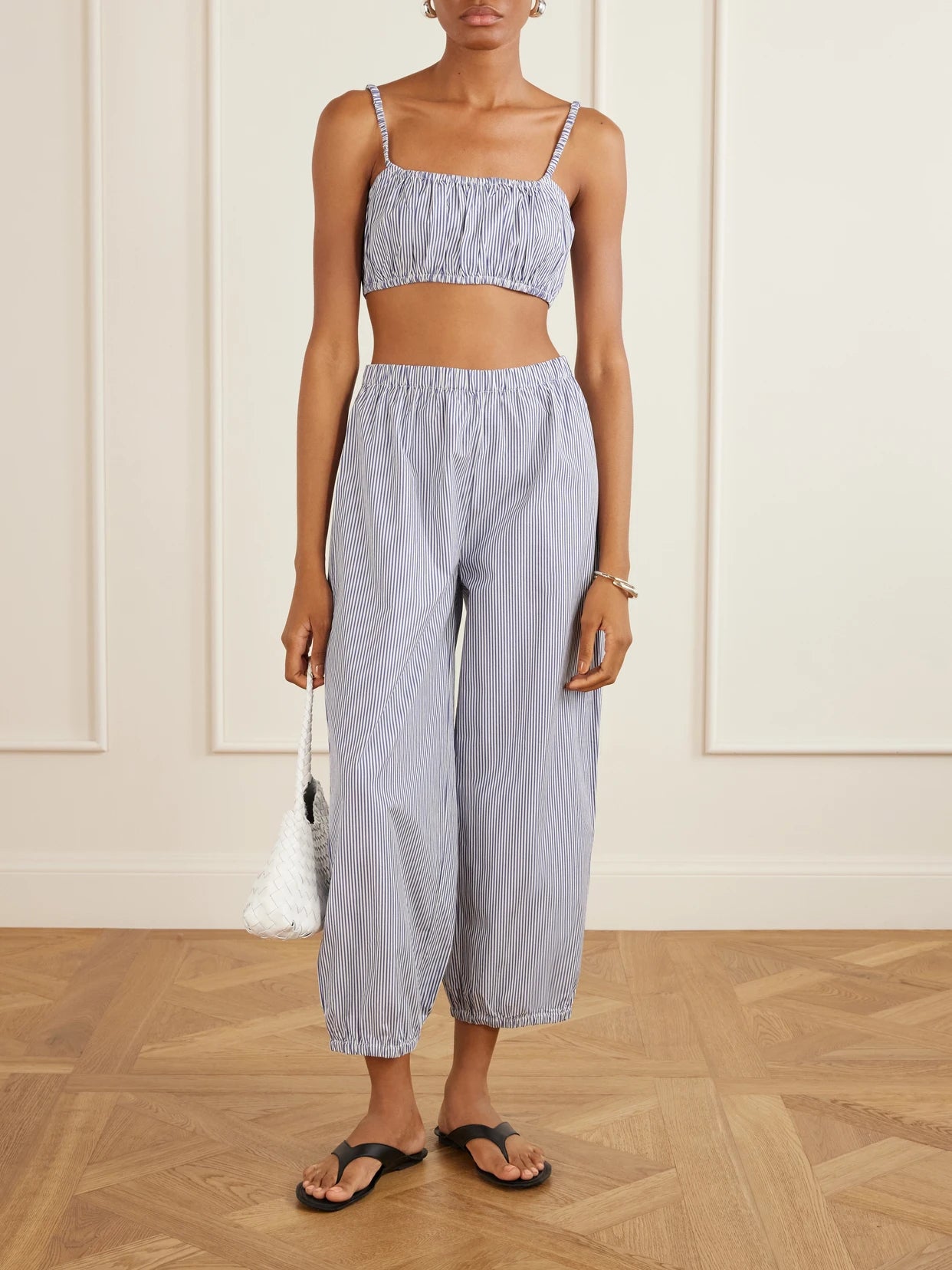 Image of a model wearing Tops. Product name - Bea Shirred Striped Cotton-poplin Bandeau Top in Navy colour by brand - Suzie Kondi