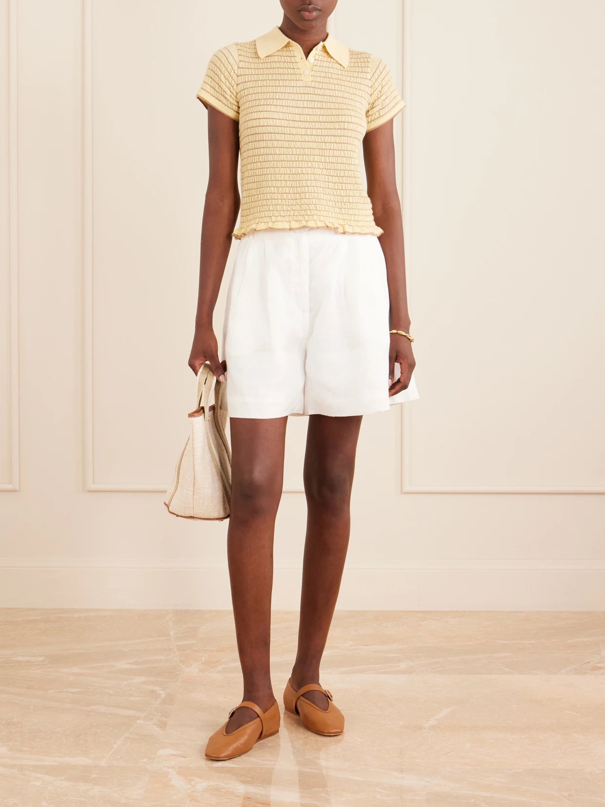 Image of a model wearing Tops. Product name - Smocked Ruffled Striped Cashmere-blend Polo Sweater in Yellow colour by brand - Guest In Residence