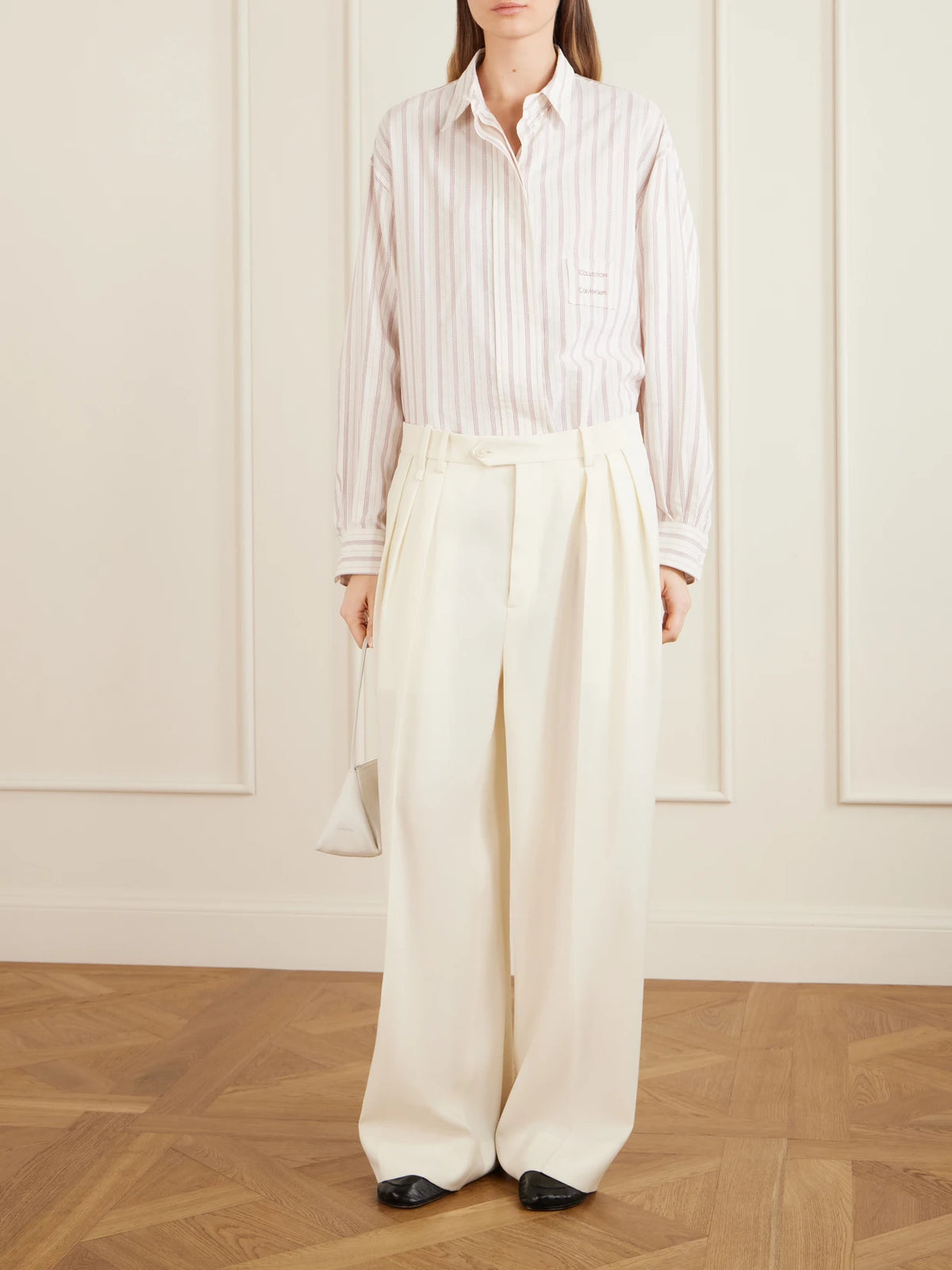 Image of a model wearing Pants. Product name - Alexandra Pleated Grain De Poudre Wool Wide-leg Pants in Ivory colour by brand - Calvin Klein Collection