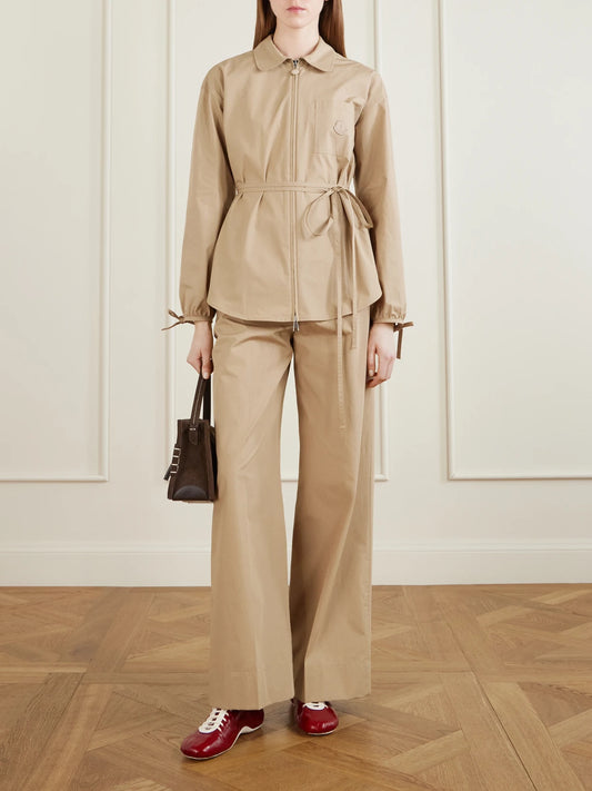 Image of a model wearing Tops. Product name - Belted Appliquéd Cotton-poplin Zip-up Shirt in Camel colour by brand - Moncler