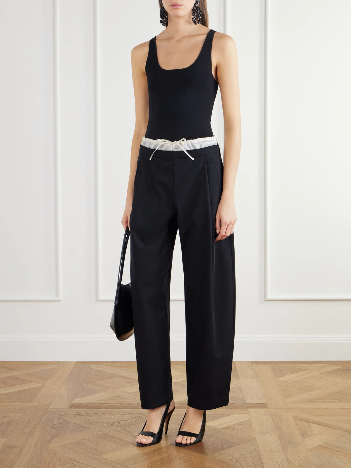 Image of a model wearing Pants. Product name - Satin-trimmed Wool-twill Barrel-leg Pants in Black colour by brand - ST. AGNI