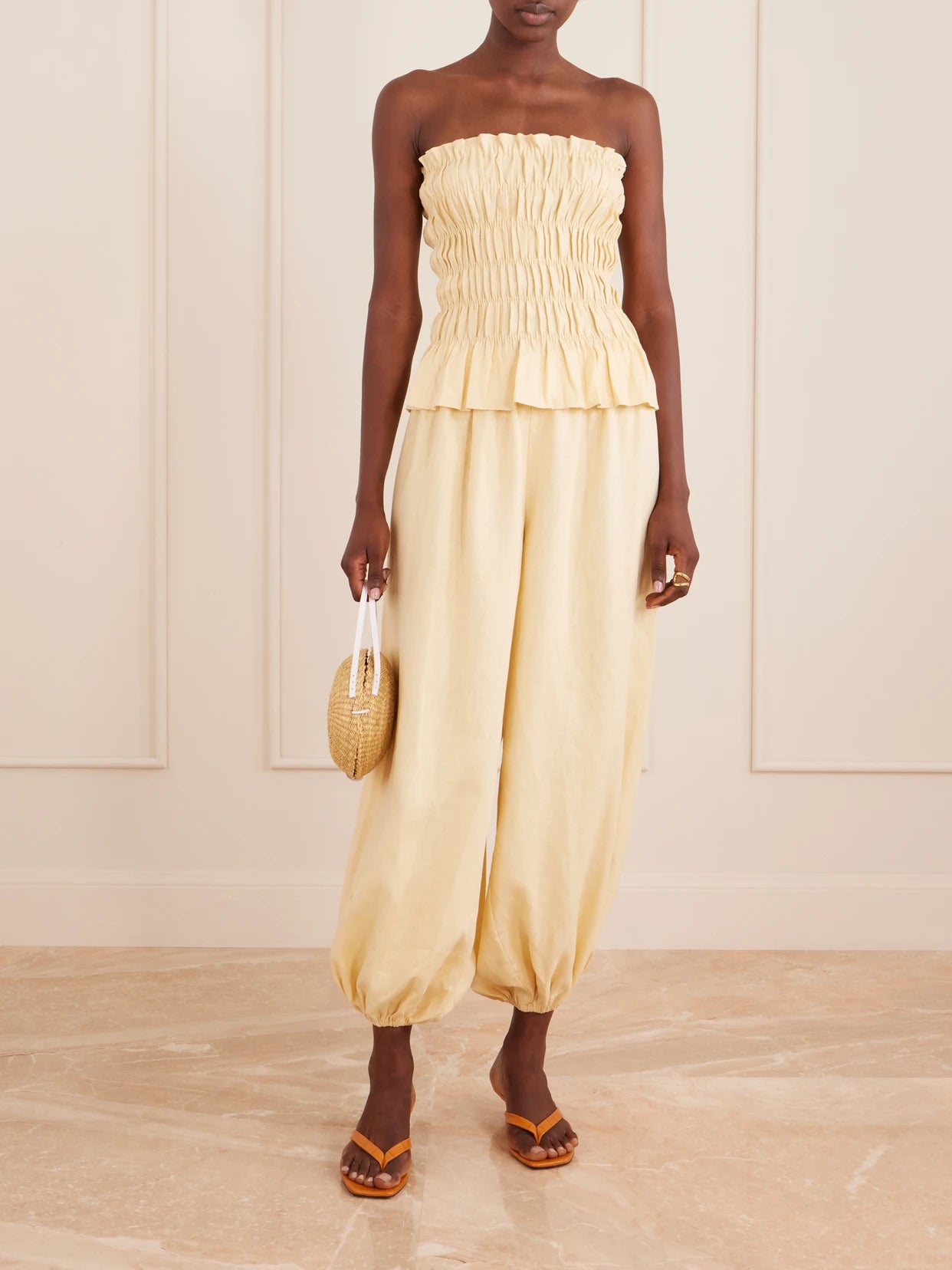 Image of a model wearing Tops. Product name - Tiera Strapless Shirred Linen Top in Yellow colour by brand - Faithfull