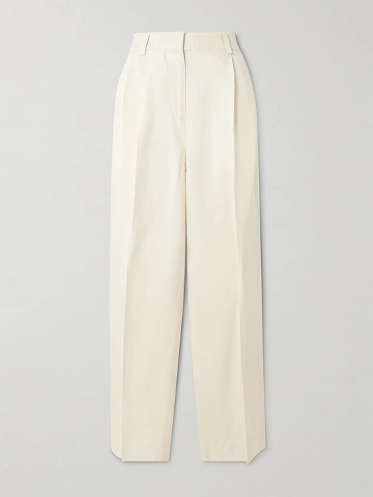 Image of a model wearing Pants. Product name - Garderob Pleated Woven Tapered Pants in Ecru colour by brand - TOTEME