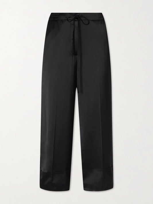 Image of a model wearing Pants. Product name - Drawstring Wide-leg Satin Pants in Black colour by brand - TOTEME