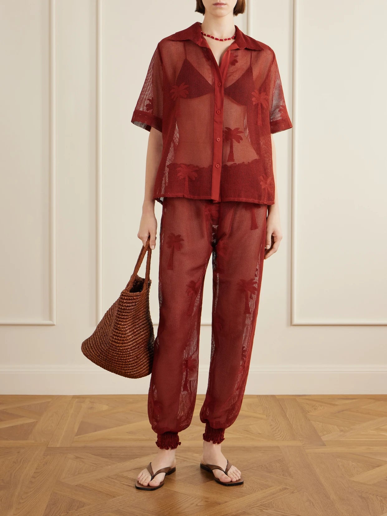 Image of a model wearing Pants. Product name - Palm Nomad Cotton-mesh Balloon Pants in Burgundy colour by brand - Johanna Ortiz