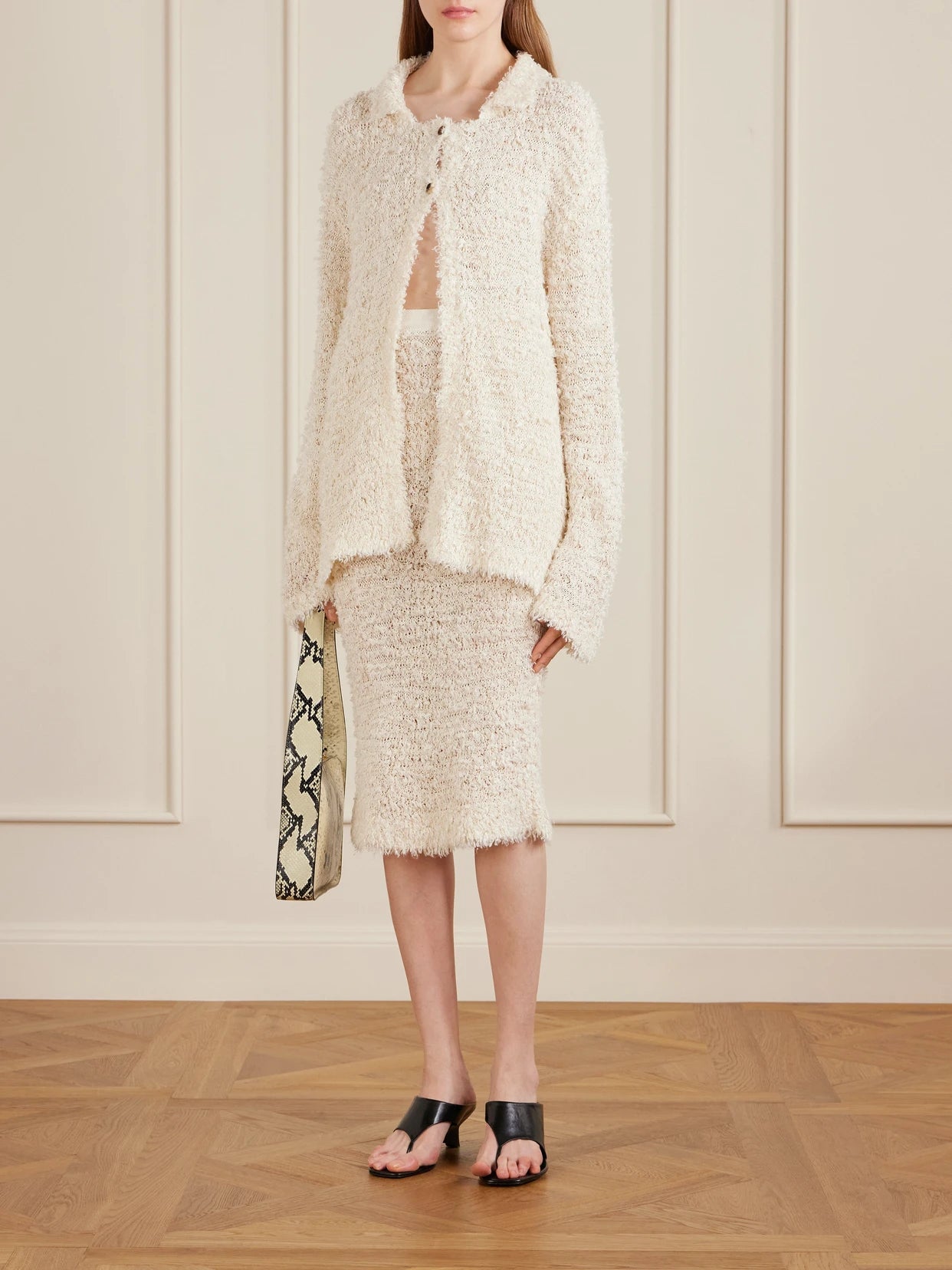 Image of a model wearing Skirts. Product name - Adela Bouclé Midi Skirt in Ivory colour by brand - KHAITE