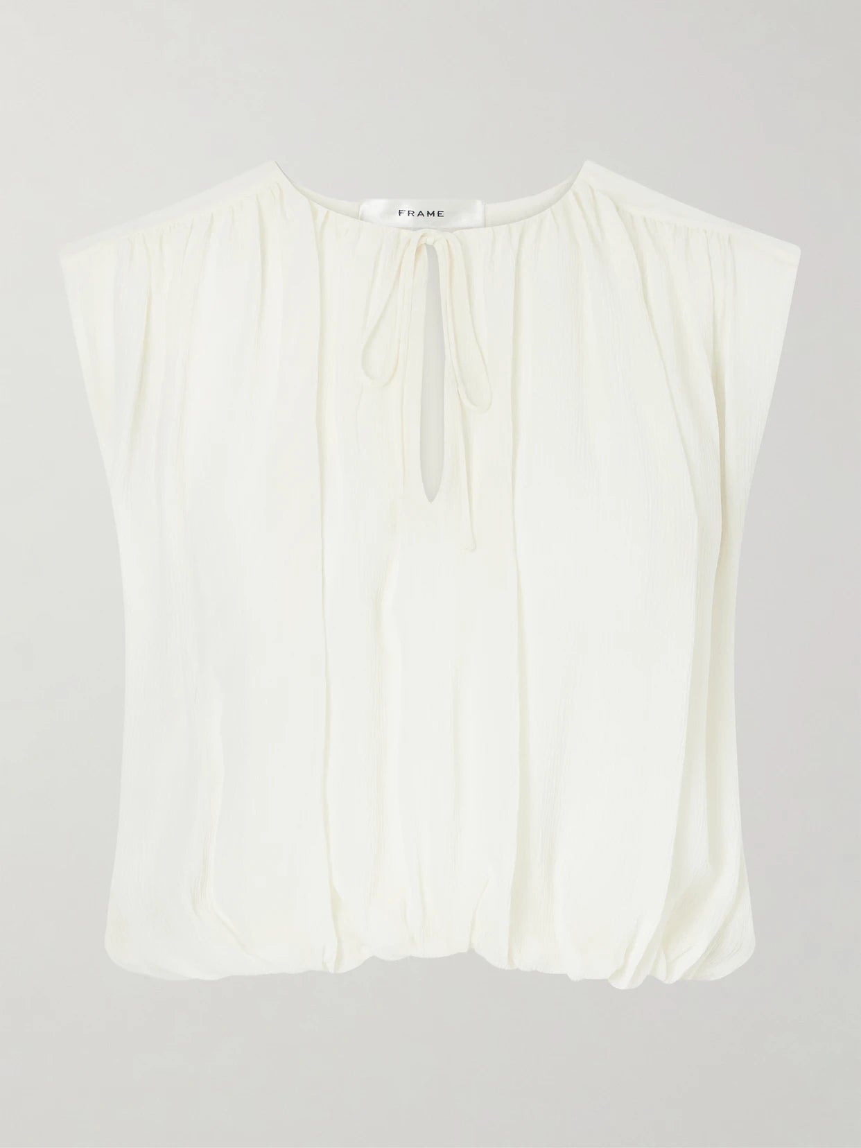 Image of a model wearing Tops. Product name - Wave Cropped Silk Top in Cream colour by brand - FRAME