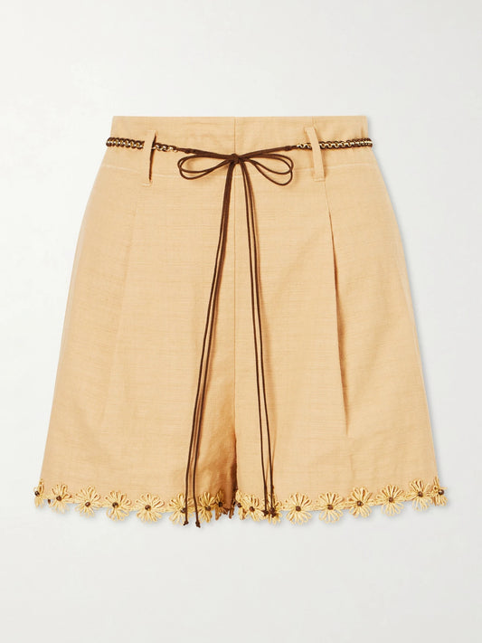 Image of a model wearing Shorts. Product name - Mahon Flower Pleated Leather And Raffia-trimmed Cotton Shorts in Cream colour by brand - Zimmermann
