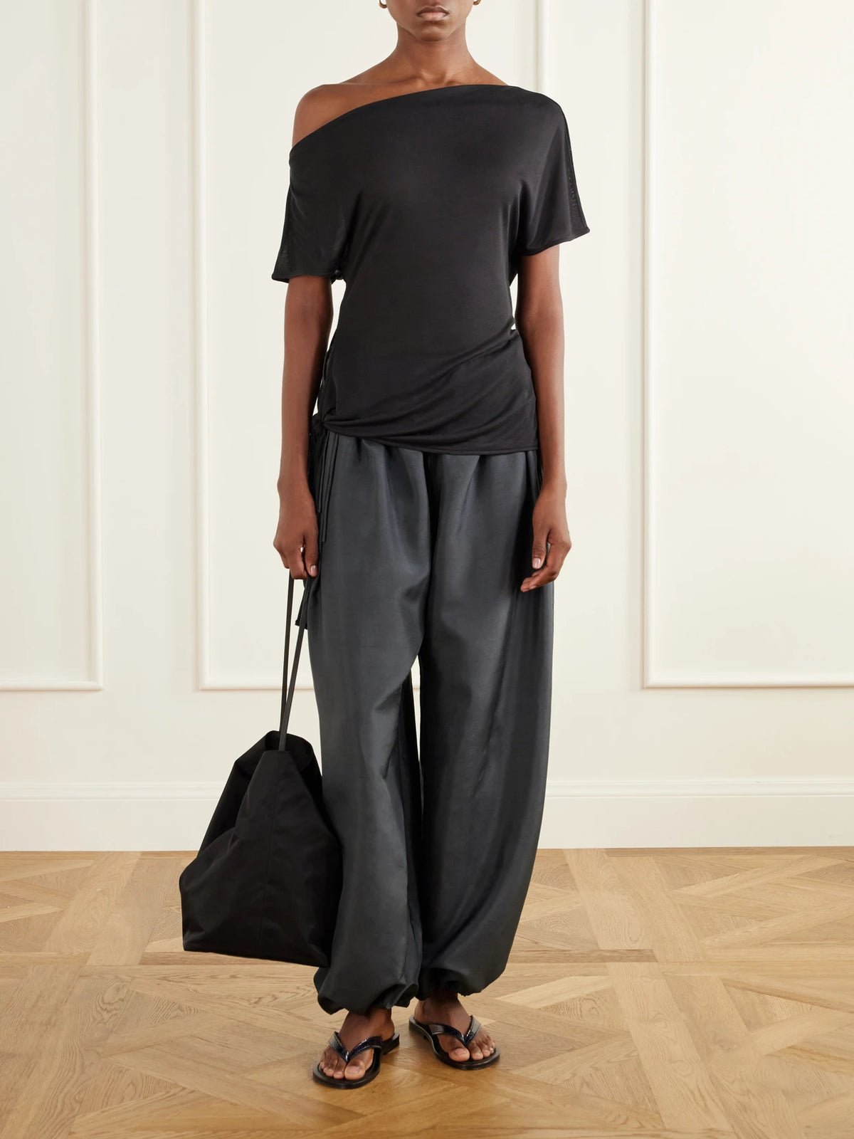 Image of a model wearing Tops. Product name - Off-the-shoulder Asymmetric Tie-detailed Tencel Lyocell Blouse in Anthracite colour by brand - ST. AGNI