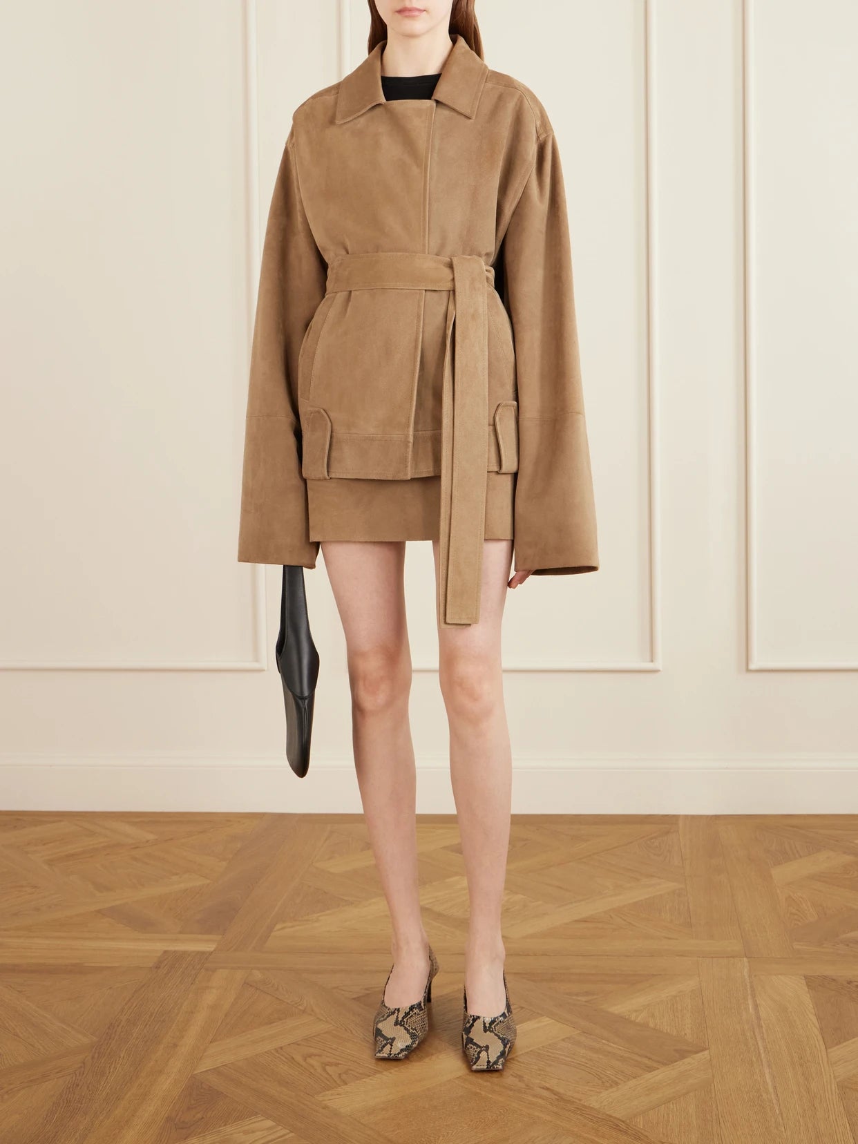 Image of a model wearing Skirts. Product name - Jett Suede Mini Skirt in Beige colour by brand - KHAITE