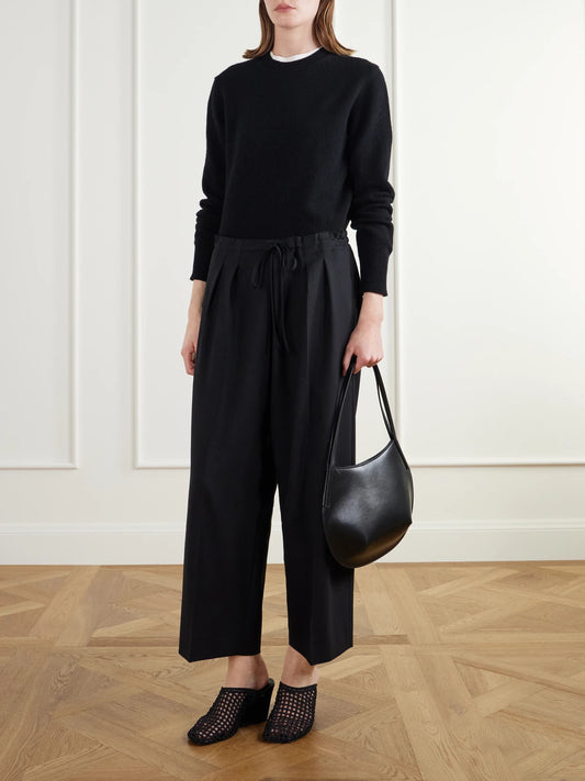 Image of a model wearing Pants. Product name - Cropped Drawstring Wool-blend Crepe Wide-leg Pants in Black colour by brand - Maria McManus