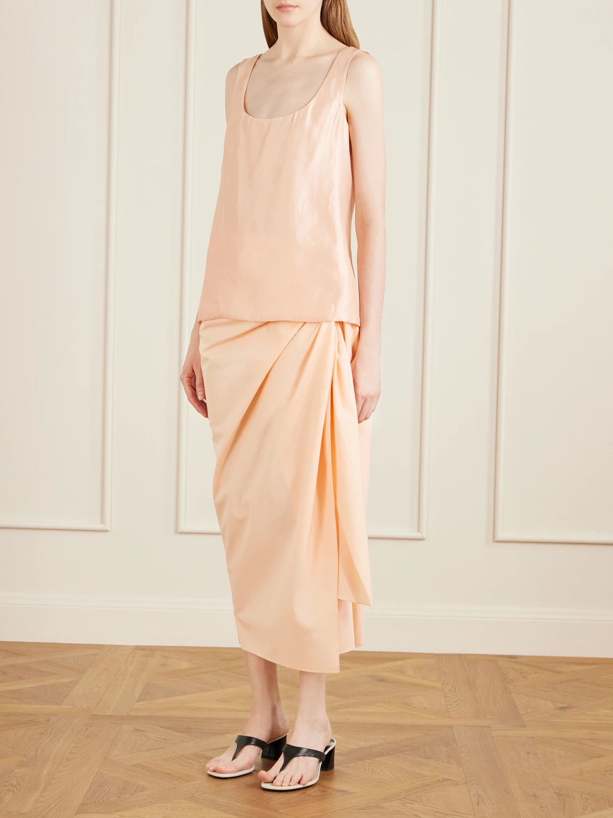 Image of a model wearing Skirts. Product name - Shay Tie-detailed Draped Cotton-poplin Wrap Midi Skirt in Peach colour by brand - KHAITE