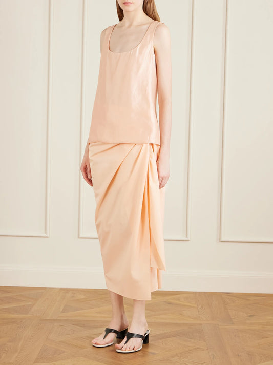 Image of a model wearing Skirts. Product name - Shay Tie-detailed Draped Cotton-poplin Wrap Midi Skirt in Peach colour by brand - KHAITE