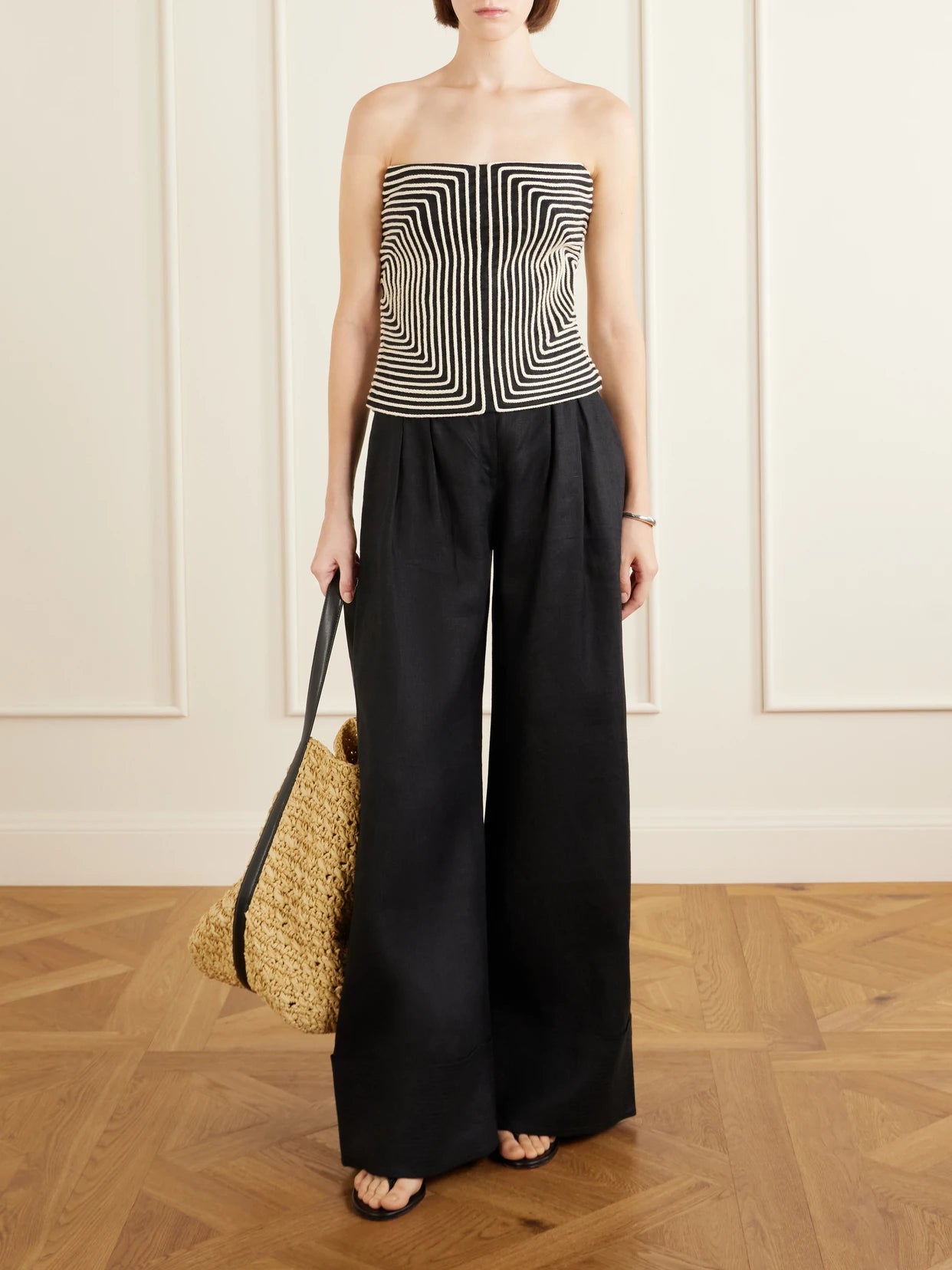 Image of a model wearing Tops. Product name - Nyota Alma Embroidered Linen-blend Bustier Top in Black colour by brand - Andres Otalora