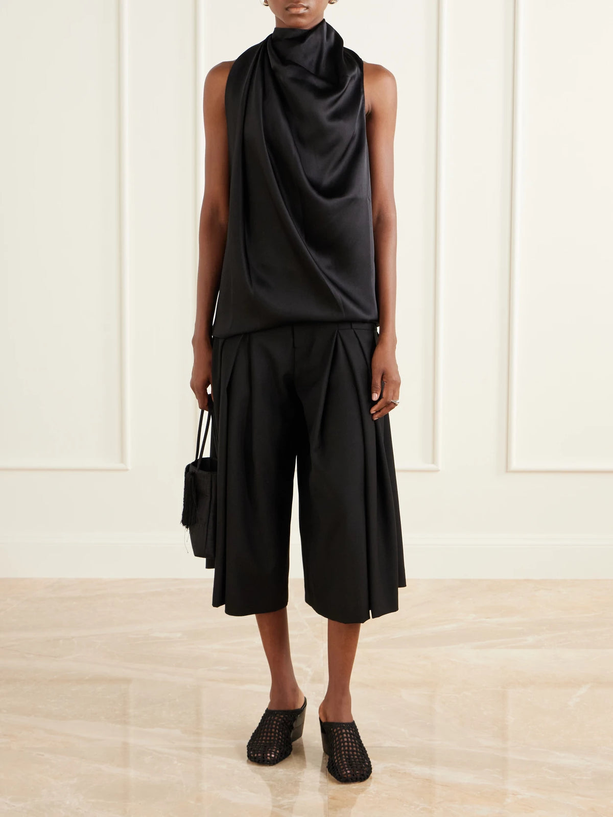 Image of a model wearing Shorts. Product name - Pleated Wool-fresco Culotte Shorts in Black colour by brand - LIBEROWE
