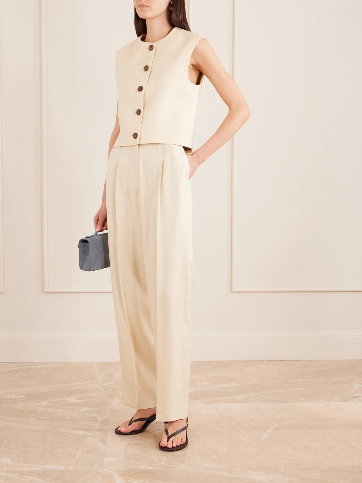 Image of a model wearing Pants. Product name - Danae Pleated Tapered Woven Pants in Beige colour by brand - BLAZÉ Milano