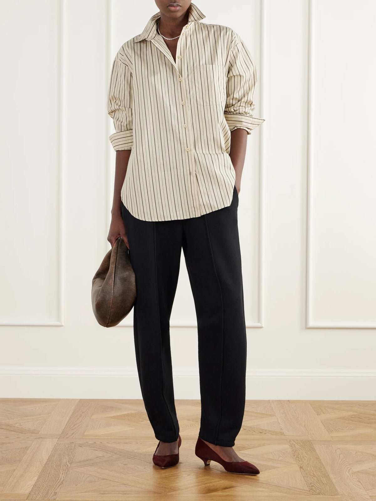 Image of a model wearing Tops. Product name - The Essential Drop-tail Striped Cotton-poplin Shirt in Cream colour by brand - Jamie Haller