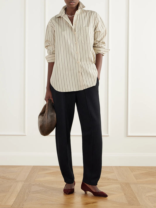 Image of a model wearing Tops. Product name - The Essential Drop-tail Striped Cotton-poplin Shirt in Cream colour by brand - Jamie Haller