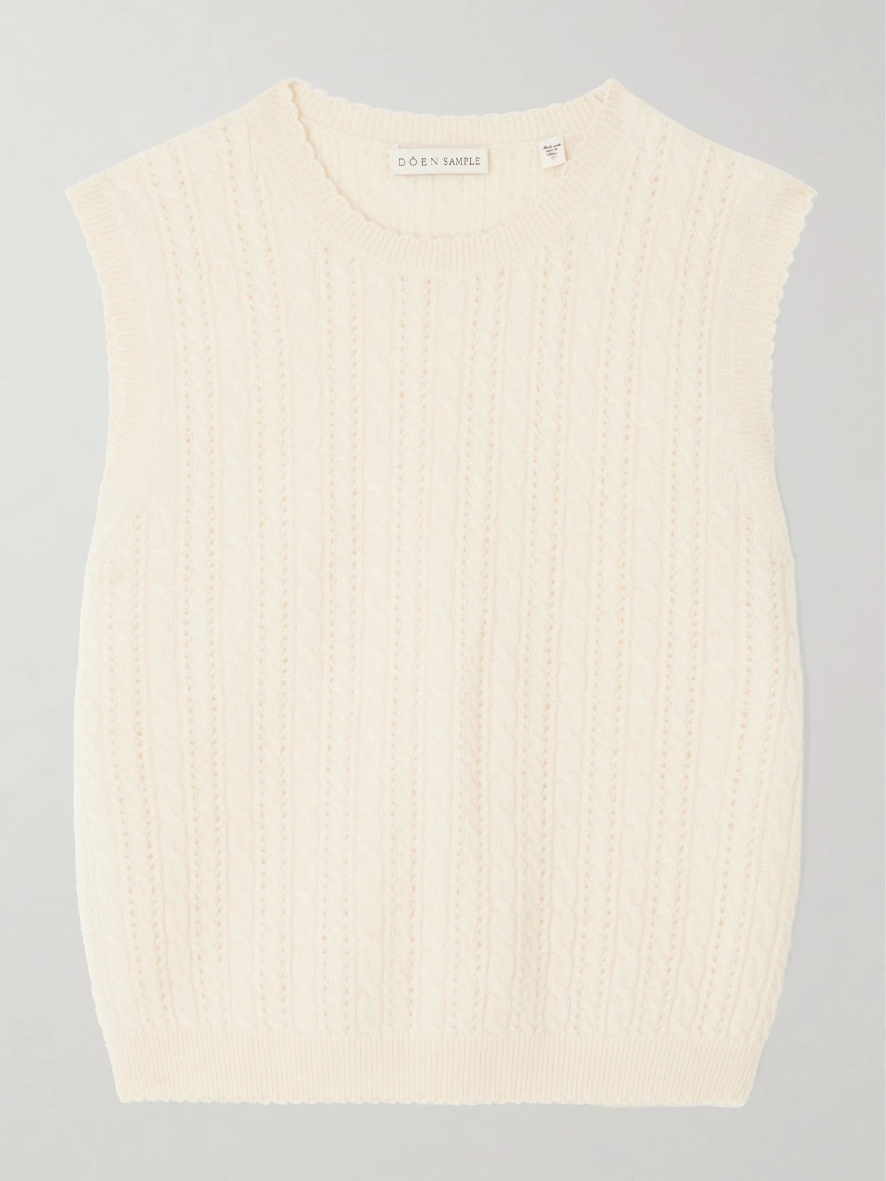 Image of a model wearing Outerwear. Product name - Louden Cropped Cable-knit Cashmere Sweater Vest in Cream colour by brand - DÔEN