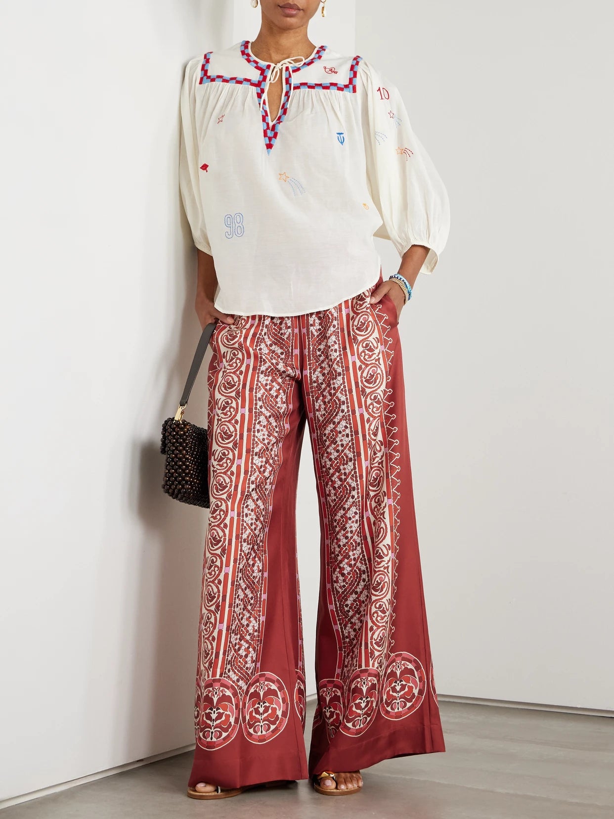 Image of a model wearing Pants. Product name - Icon Palazzo Printed Silk-twill Wide-leg Pants in Red colour by brand - La DoubleJ