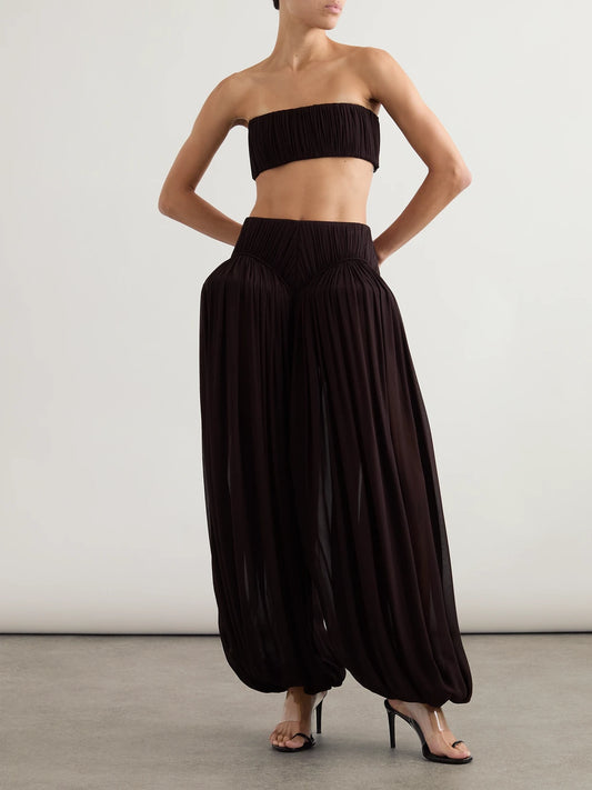 Image of a model wearing Pants. Product name - Pleated Crepe Balloon Pants in Dark brown colour by brand - Alaïa
