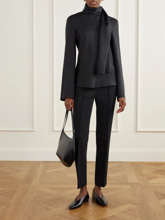 Image of a model wearing Tops. Product name - Tie-detailed Silk-satin Blouse in Black, Cream colour by brand - RÓHE