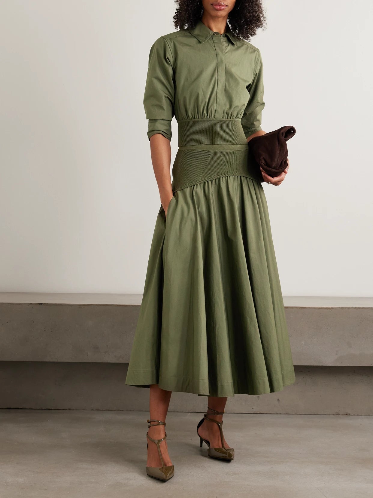 Image of a model wearing Skirts. Product name - Ovie Pleated Ribbed-knit Trimmed Cotton-poplin Midi Skirt in Green colour by brand - SIMKHAI